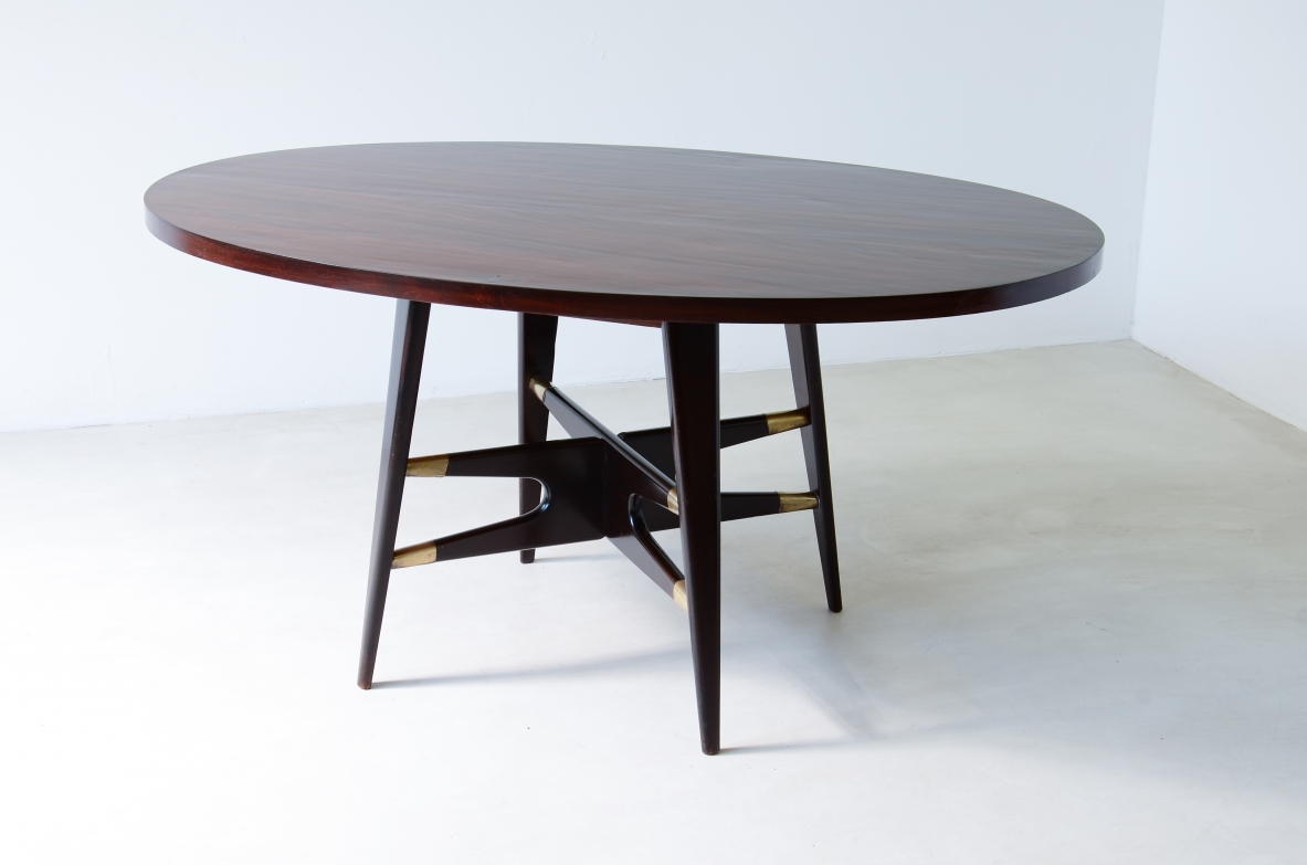 Gianni Vigorelli  Elegant oval table in stained wood with four-legged uprights and important cross with brass tips.  Italian manufacture, attr. Vigorelli. 1950 approx.