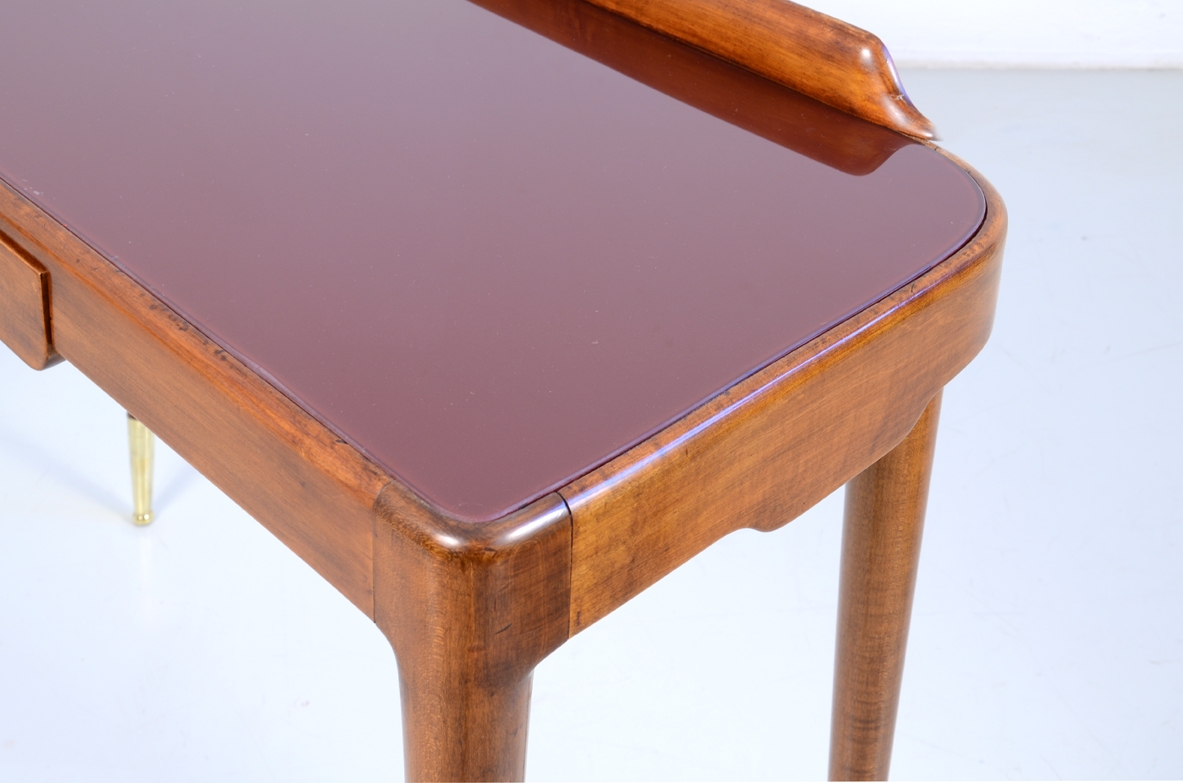 Elegante console con sottili gambe tornite e lunghi puntali in ottone, piano in opaline rosso scuro. Italia 1950ca.