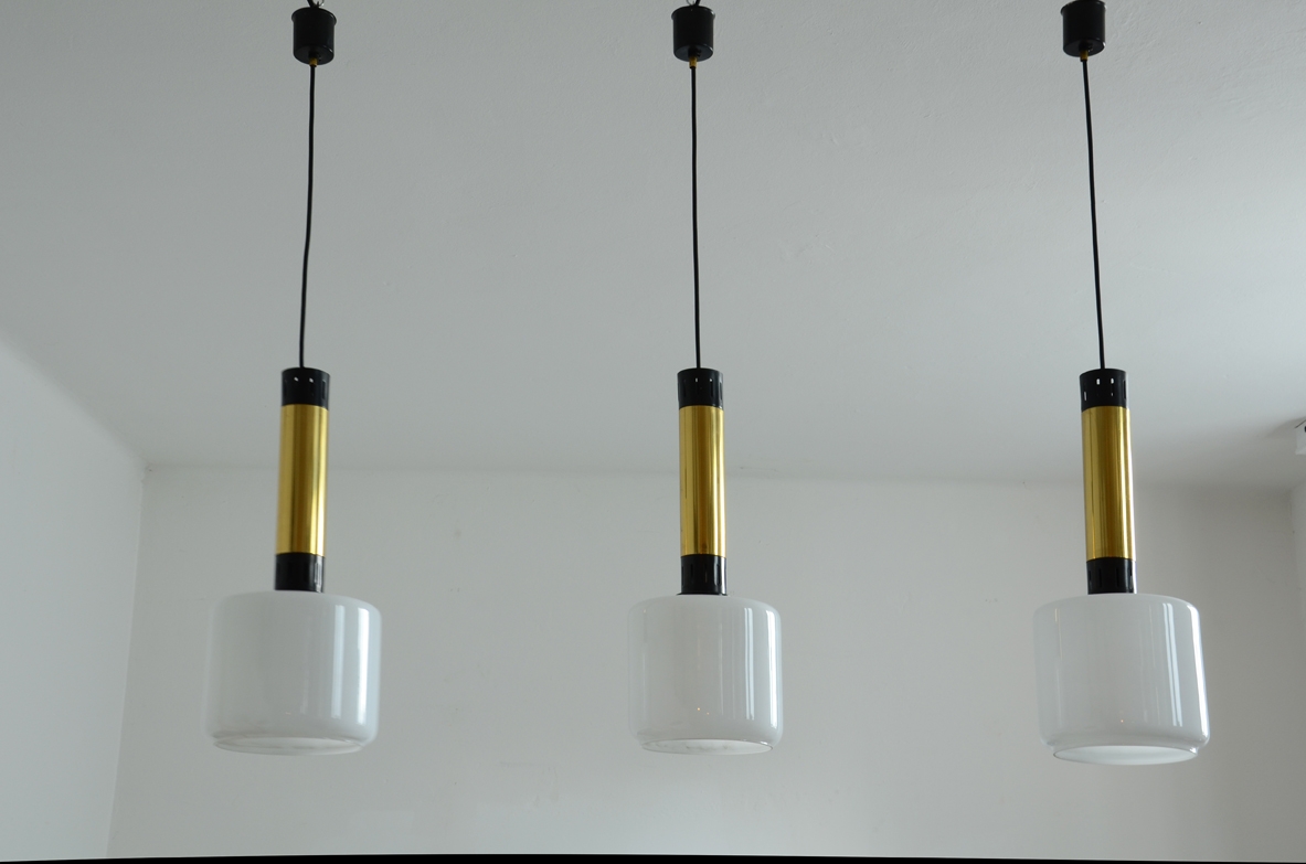 Stilnovo, tre lampade a sospensione con struttura in ottone, metallo laccato e diffusori in vetro opalino. Stilnovo, tre lampade a sospensione con struttura in ottone, metallo laccato e diffusori in vetro opalino.