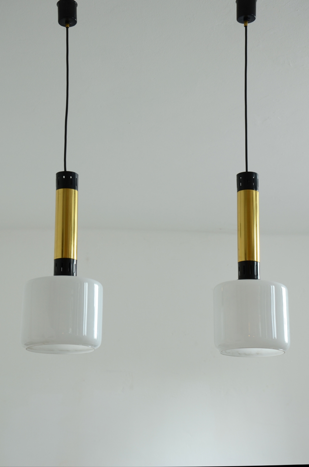 Stilnovo, tre lampade a sospensione con struttura in ottone, metallo laccato e diffusori in vetro opalino. Stilnovo, tre lampade a sospensione con struttura in ottone, metallo laccato e diffusori in vetro opalino.