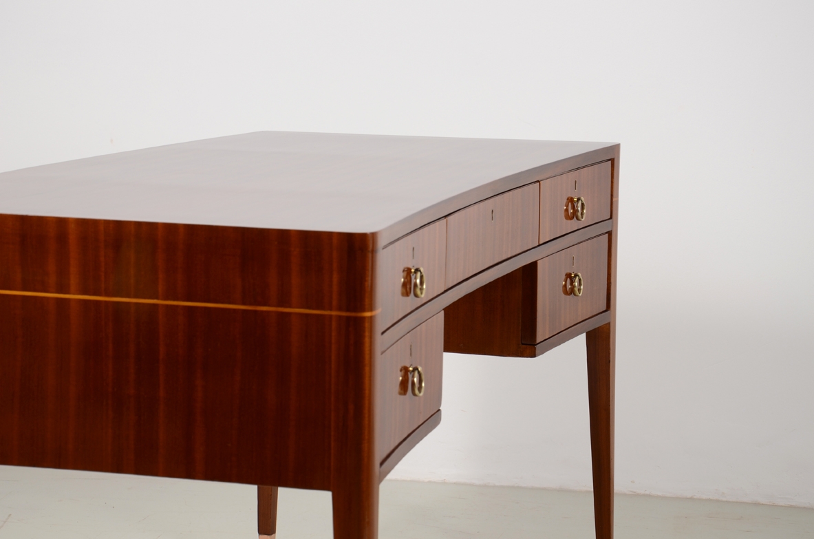 Italian elegant and curved 1950's desk in walnut and maplewood with five drawers and brass tips.