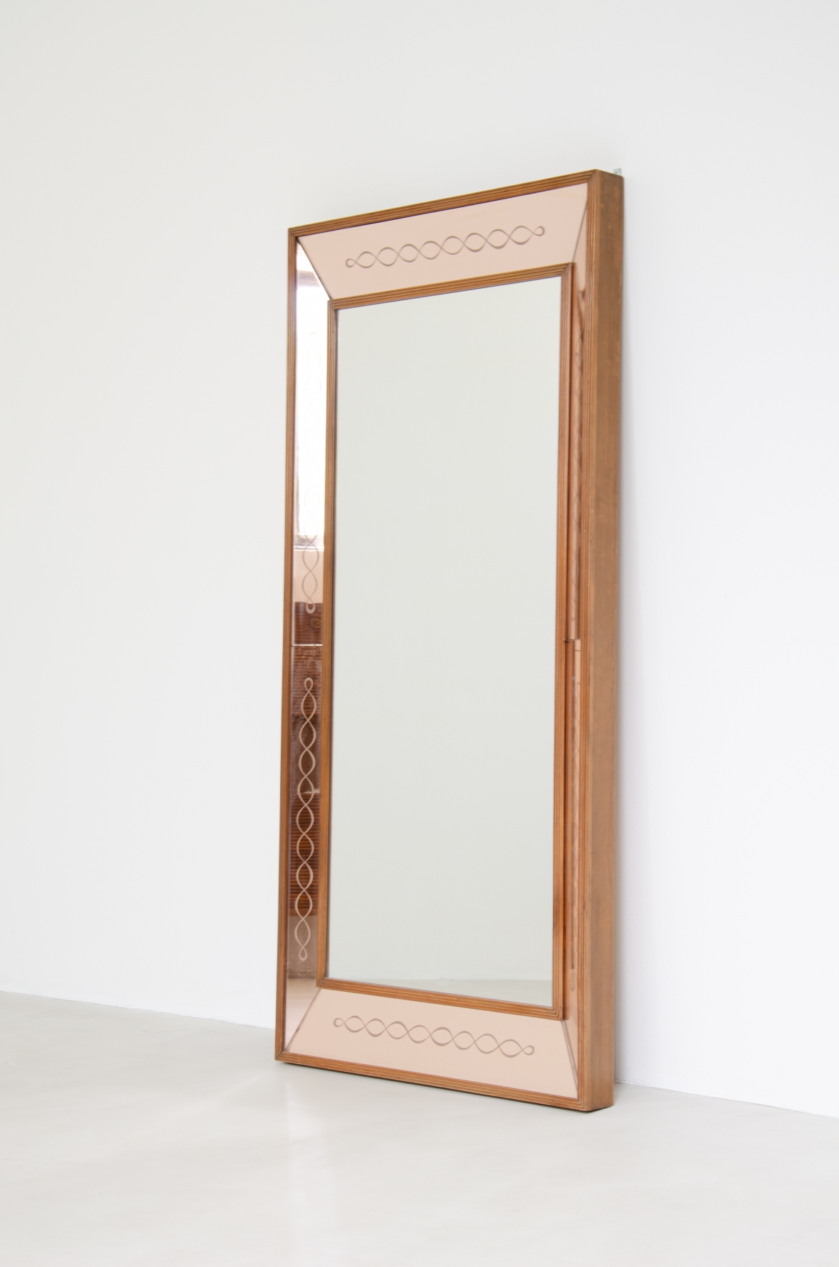 Grande specchiera con specchi laterali inclinati color cipria incisi con motivo a nastro, cornice in legno. Manifattura Italiana anni 40.