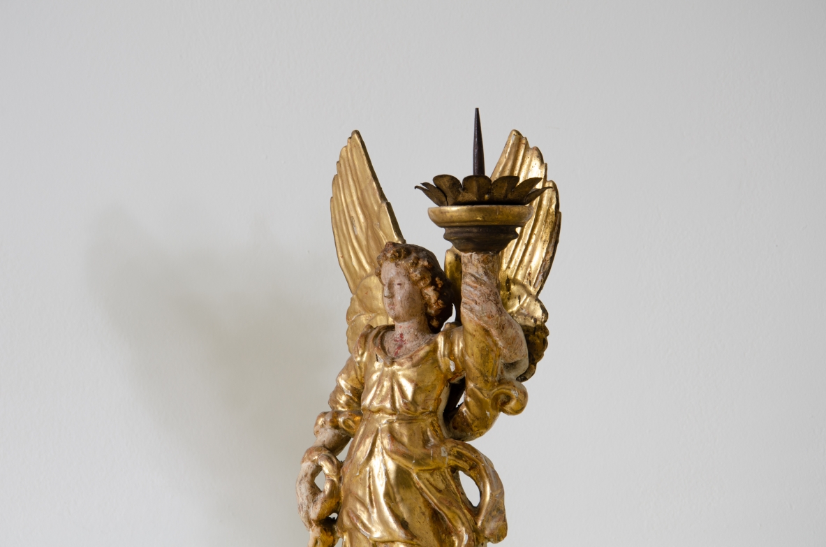 Coppia di angeli in legno laccato e dorato che reggono una cornucopia con corona in metallo dorato.   Italia centrale, epoca Barocco, seconda metà del XVII secolo.