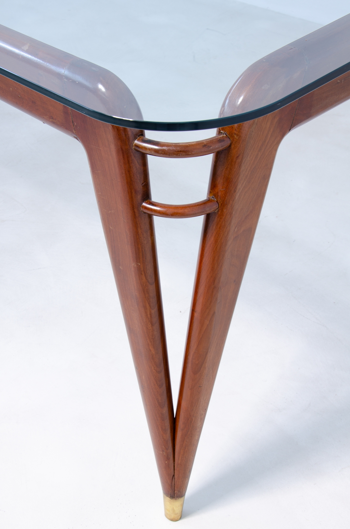 Tavolo in mogano con puntali in ottone e piano in cristallo di grande spessore.  Manifattura italiana, 1950ca.