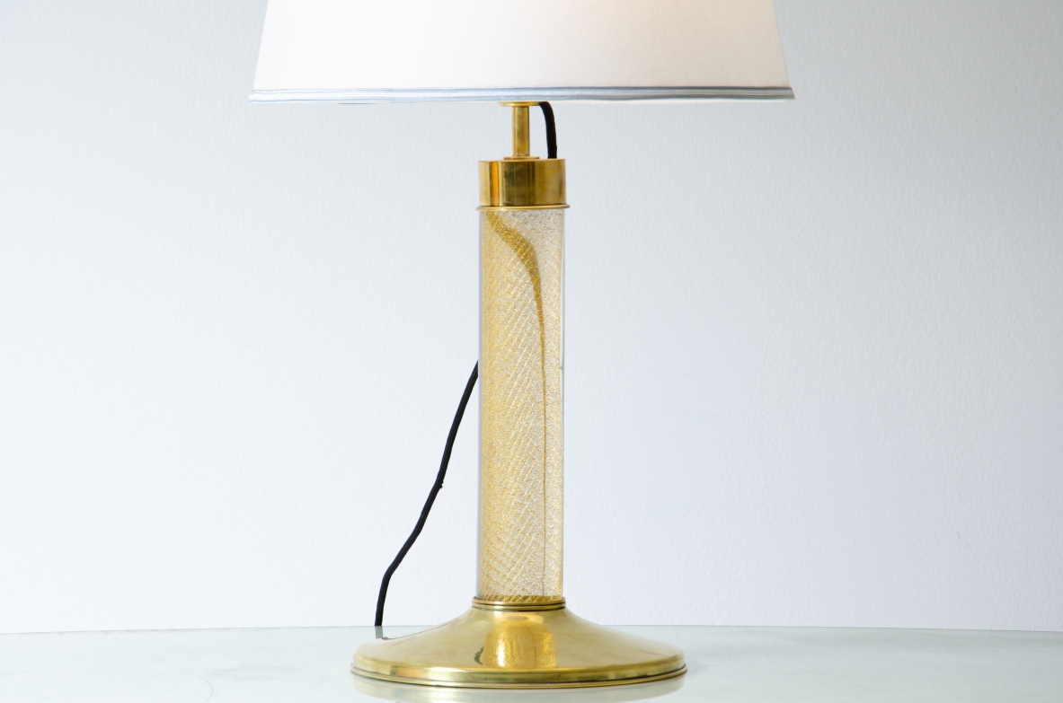 Tommaso Barbi. Lampada da tavolo con base in ottone e stelo in vetro di Murano, cappello in tessuto.  Manifattura italiana, 1940ca. Tommaso Barbi. Lampada da tavolo con base in ottone e stelo in vetro di Murano, cappello in tessuto.  Manifattura italiana, 1940ca.