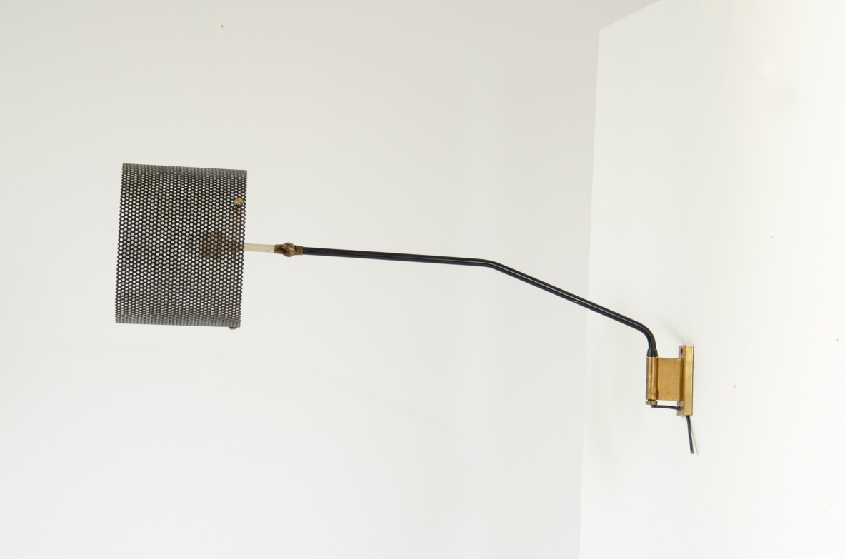 Stilnovo, lampada da parete con braccio tubolare e paralume in rete metallica. Dettagli in ottone. 1950ca.  Etichetta del produttore.