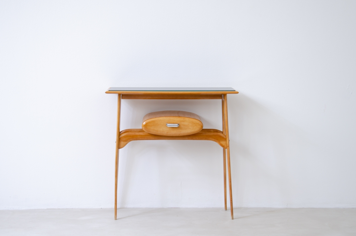 Piccola console in legno biondo con piano il vetro opaline e cassetto ovale.  Manifattura italiana 1950ca.