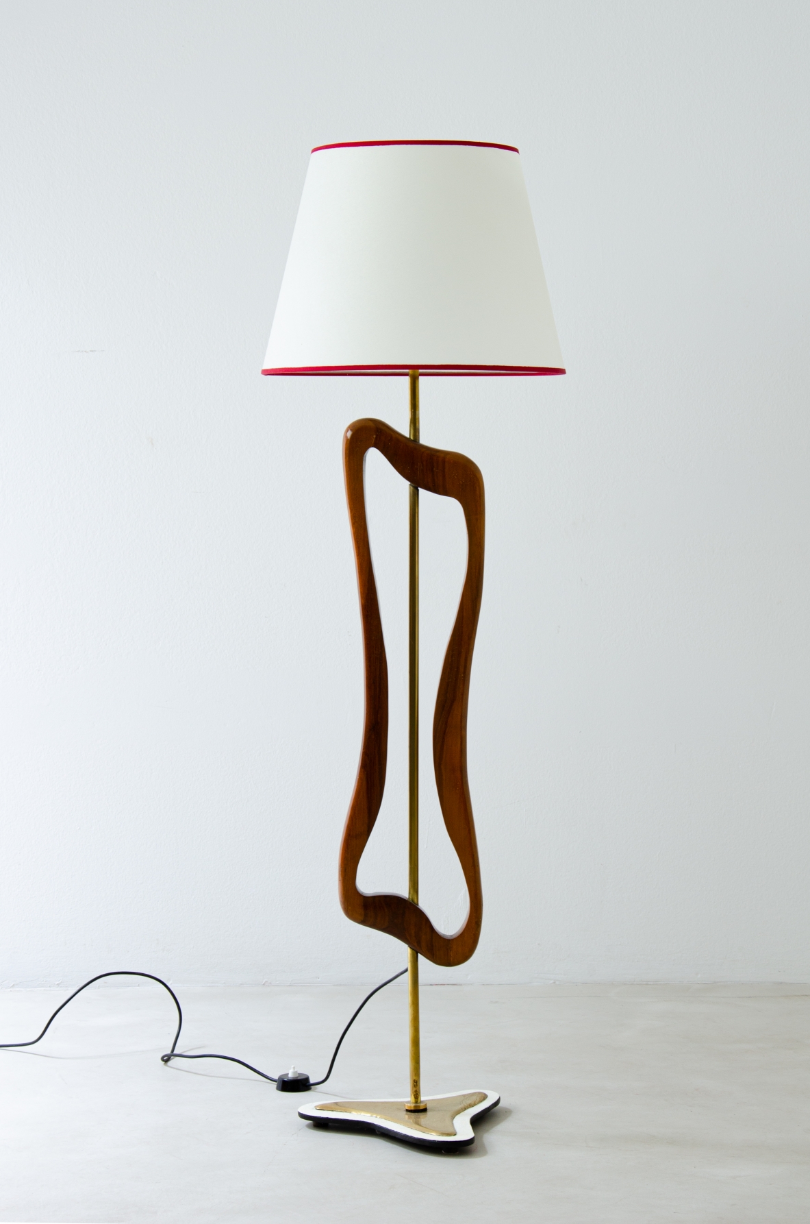 Rara lampada/scultura da terra in ottone e legno sagomato con cappello in pergamena. Manifattura italiana, 1950ca. Rara lampada/scultura da terra in ottone e legno sagomato con cappello in pergamena. Manifattura italiana, 1950ca.