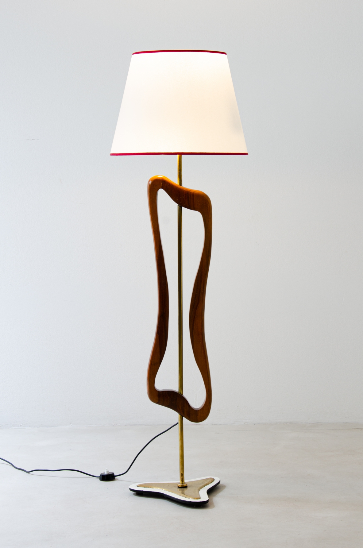Rara lampada/scultura da terra in ottone e legno sagomato con cappello in pergamena. Manifattura italiana, 1950ca. Rara lampada/scultura da terra in ottone e legno sagomato con cappello in pergamena. Manifattura italiana, 1950ca.