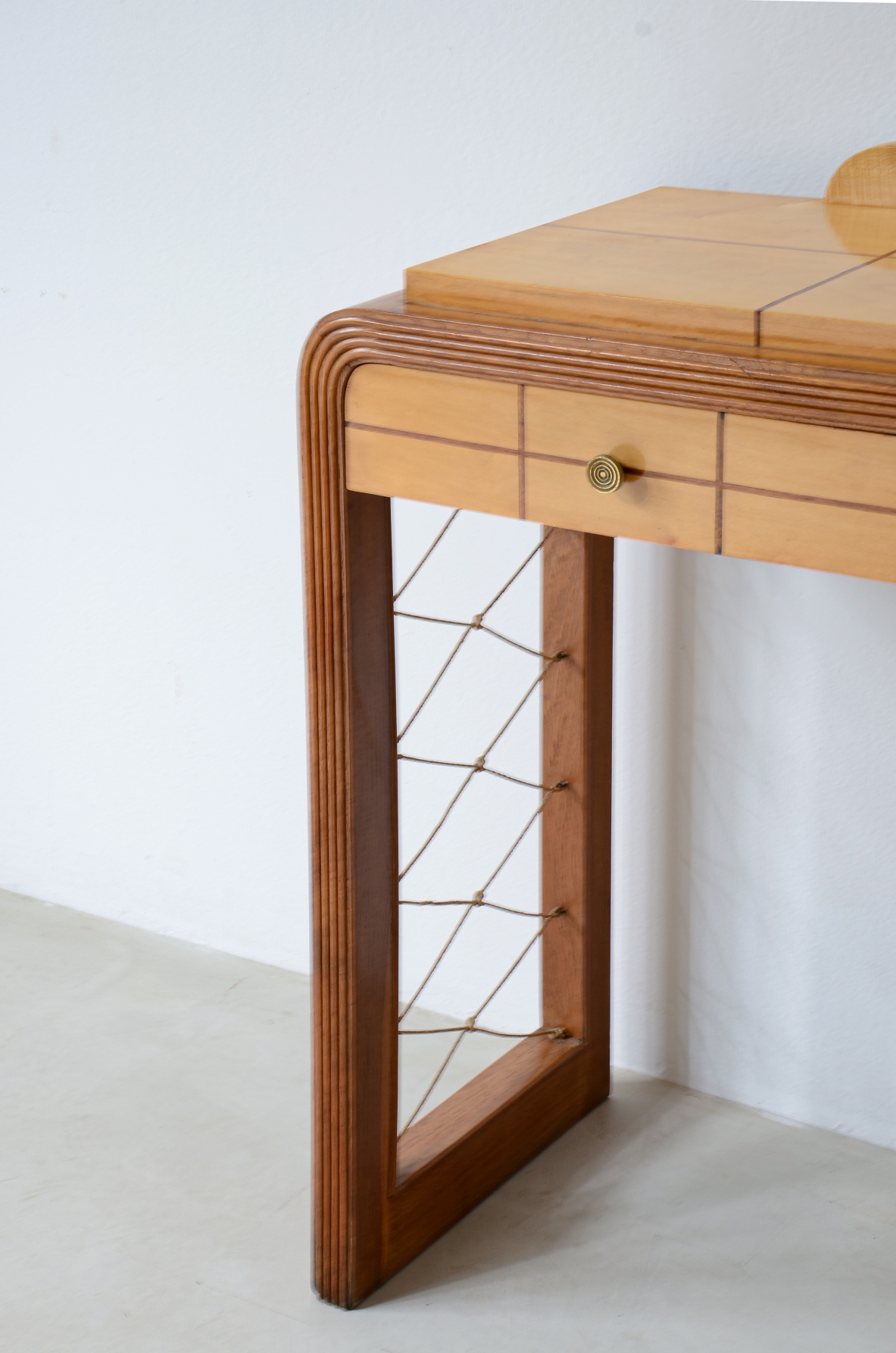 Piccola console in legno biondo con filettature sul piano, due cassetti sul fronte e montanti con intrecci geometrici in corda.