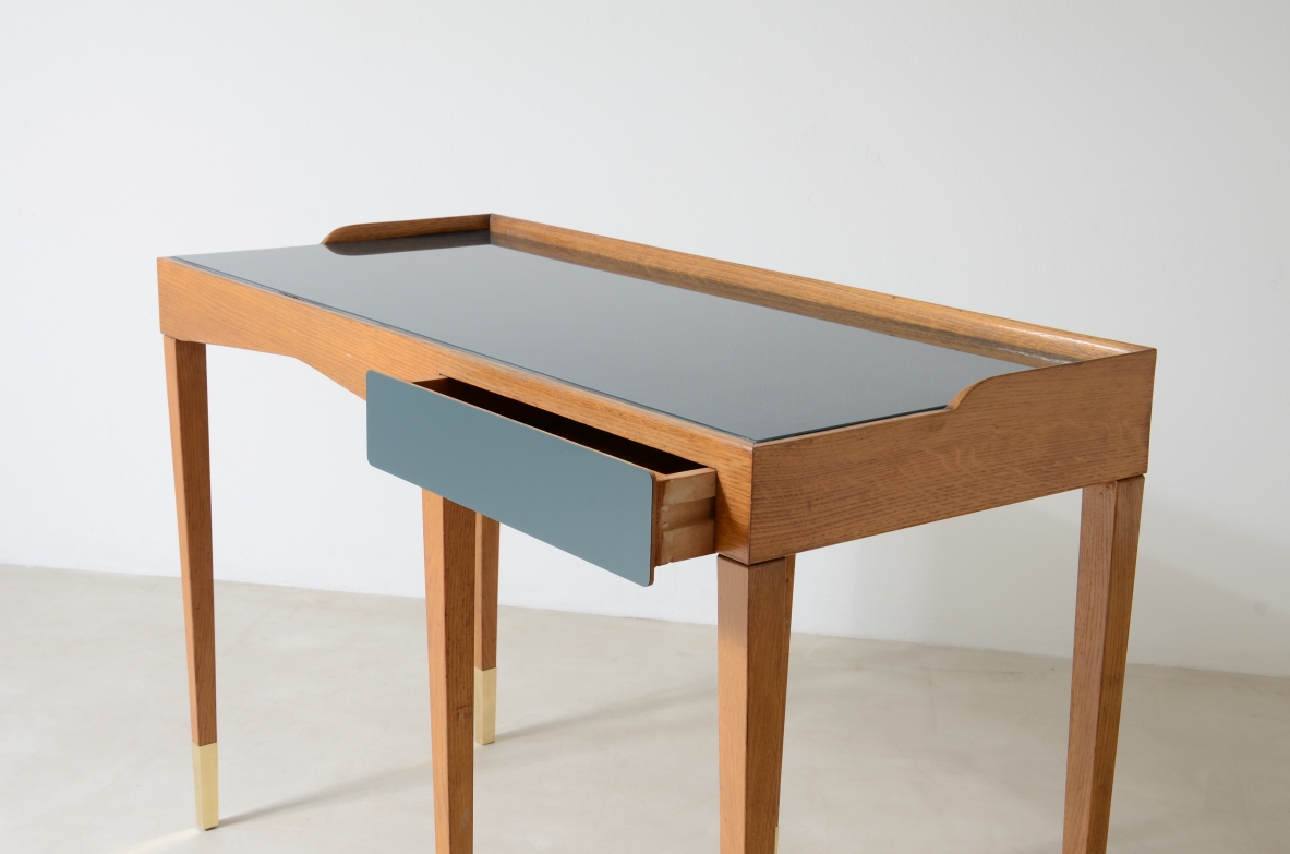 Refined oak writing desk with petrol green opaline glass top and backsplash.  Shaped drawer of the same color covered in polypropylene. Long thin legs with brass tips.  Attributed to Gio Ponti, early 1950s manufacture.