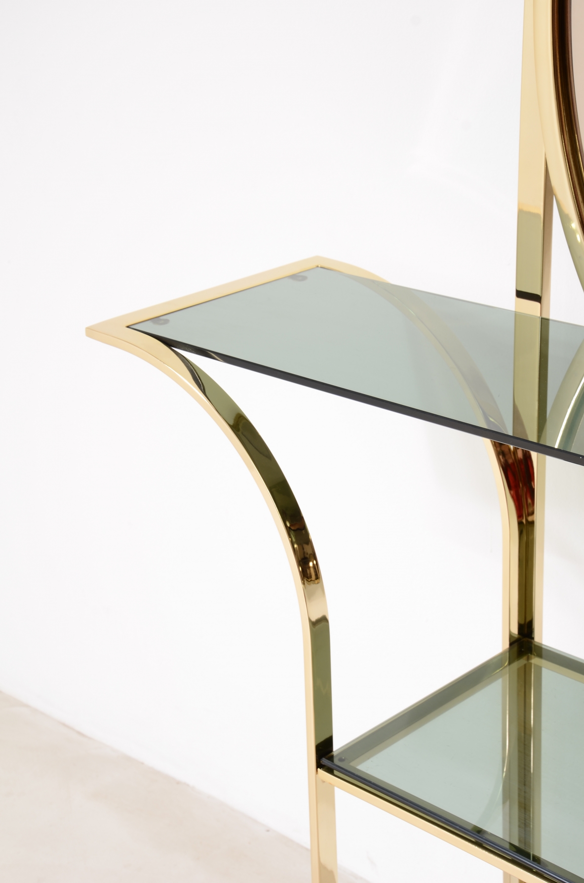 Console table in curved brass with shelves in grey blue glass and a huge mirror in burned brown color.  1970s Italian manufacture. 