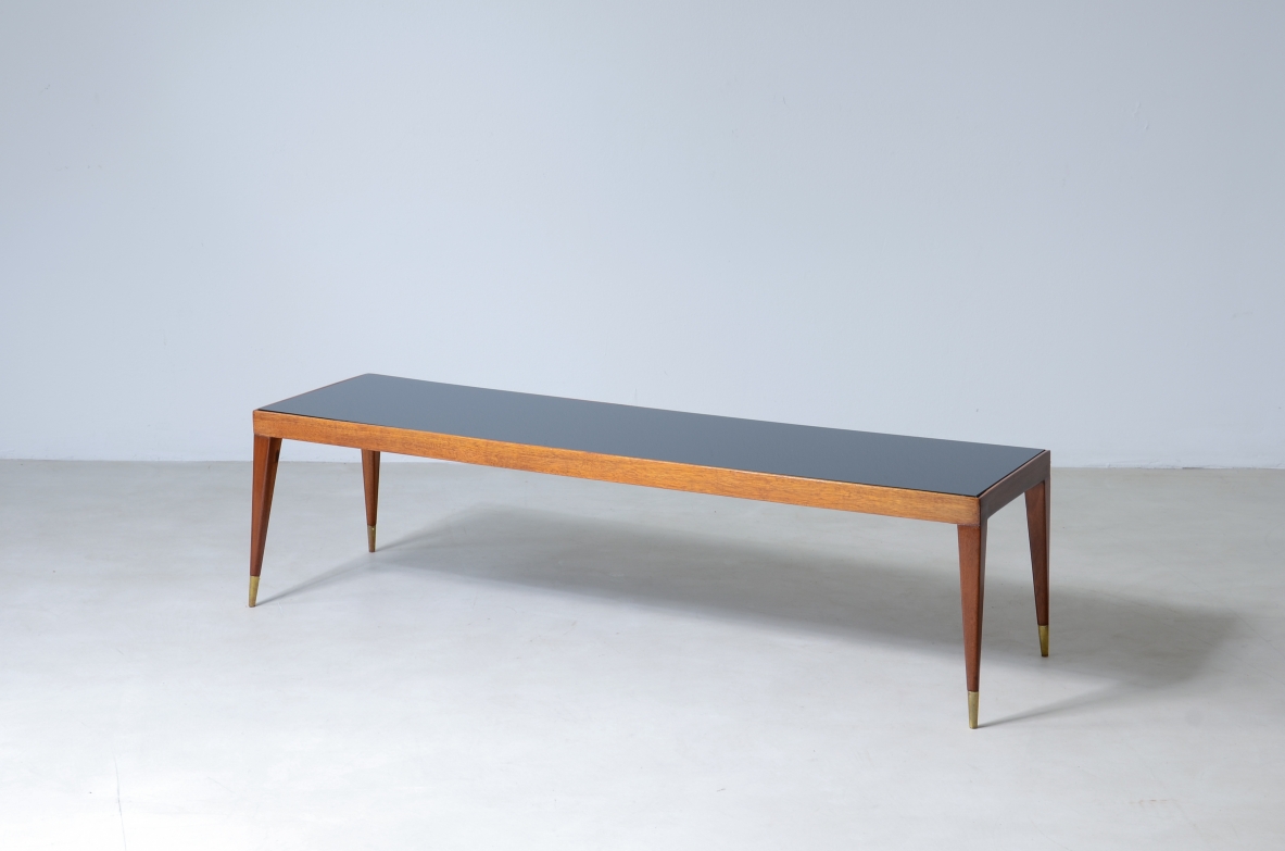 Elegante tavolo basso in mogano chiaro con puntali in ottone e piano in vetro.  Manifattura italiana, 1950ca. Elegante tavolo basso in mogano chiaro con puntali in ottone e piano in vetro.  Manifattura italiana, 1950ca.