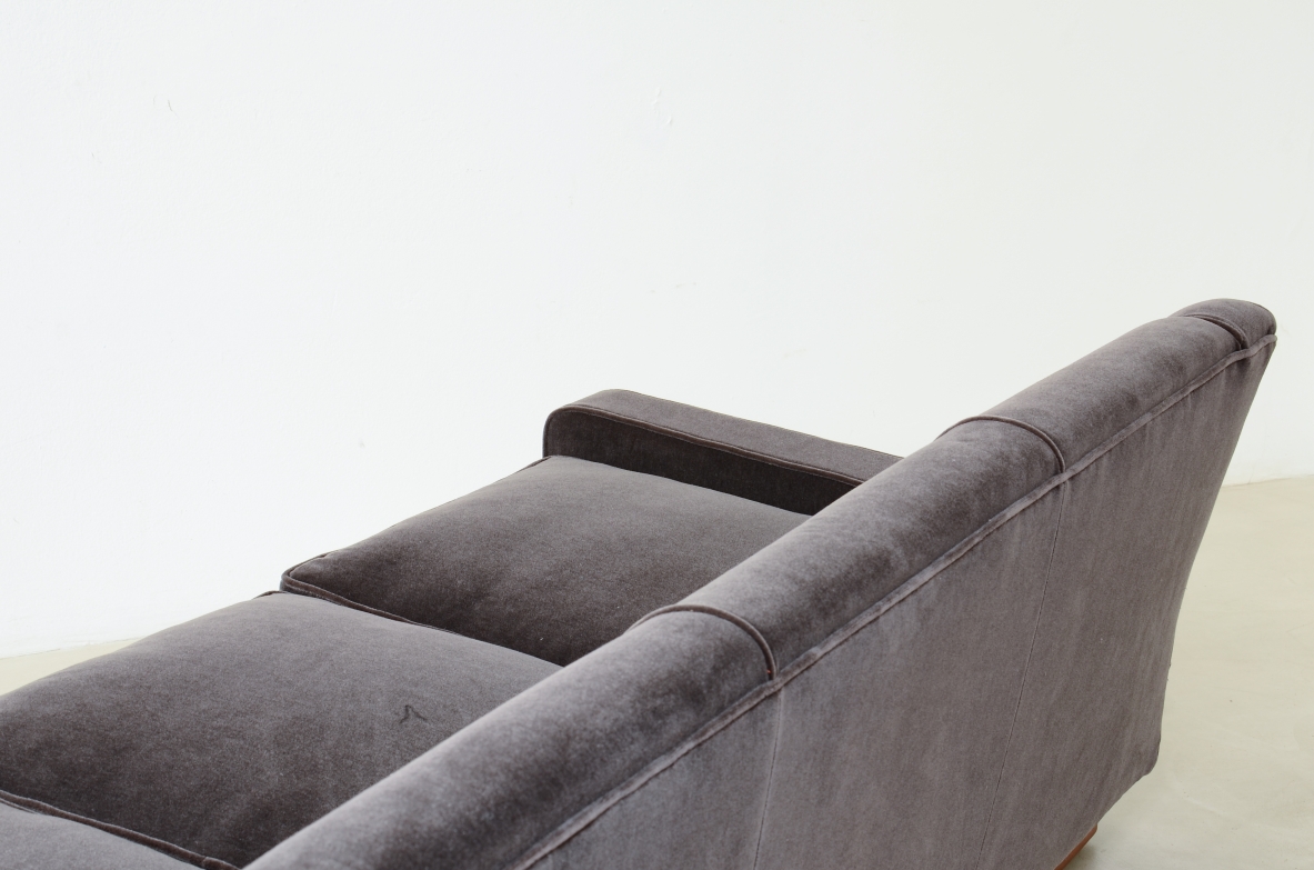 Three-seater sofa with wooden base and padded velvet upholstery.