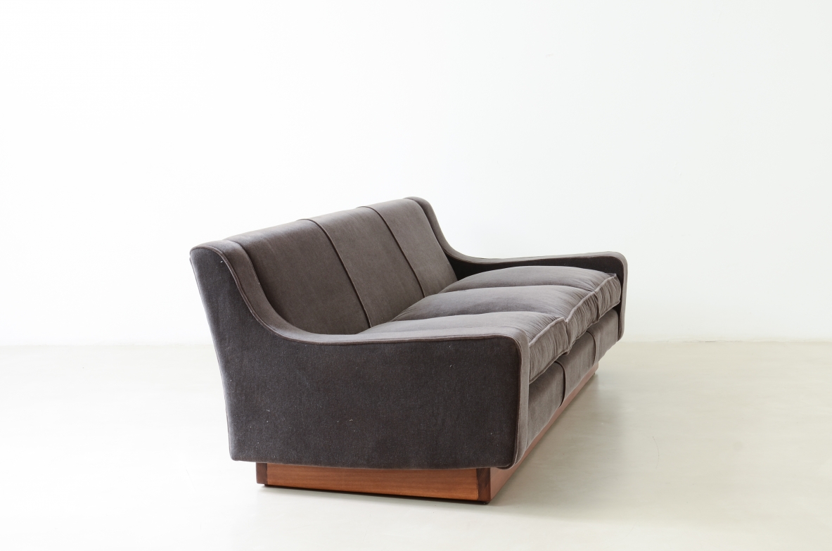 Three-seater sofa with wooden base and padded velvet upholstery.