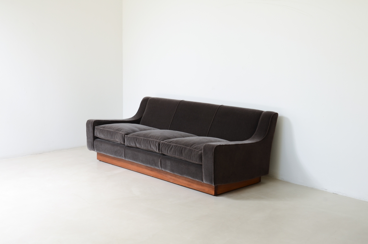 Three-seater sofa with wooden base and padded velvet upholstery.