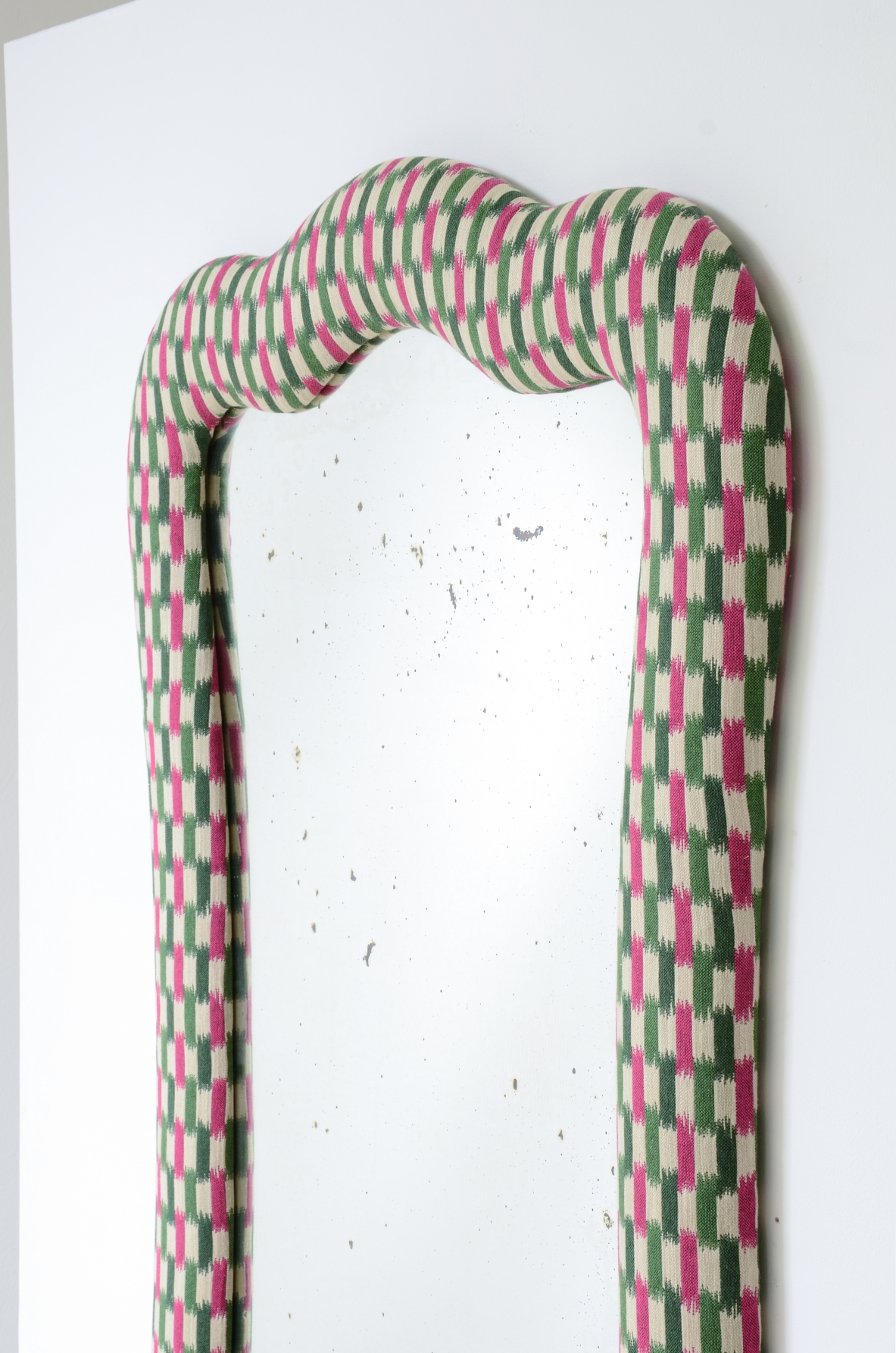 Large mirror with a shaped frame and fabric covering.Italian manufacture,ca. 1880-1900.