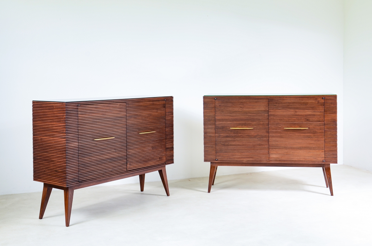 Paolo Buffa  Due eleganti mobili contenitore a due ante con fronte e fianchi in legno grissinato, piano in vetro opaline e lunghi piedi tronco piramidali, maniglie in ottone sagomato.  Manifattura anni 50'.