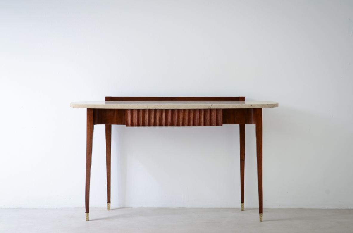 Elegant console moved on the front and sides, with two ribbed wooden drawers and oval travertine top, brass crown tips.