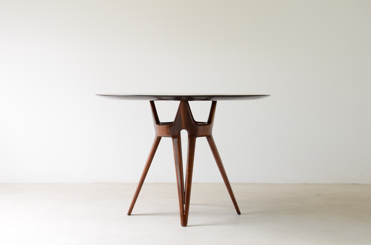 Elegant table with carved wooden base and veneered top.  Italian manufacture, ca. 1950.